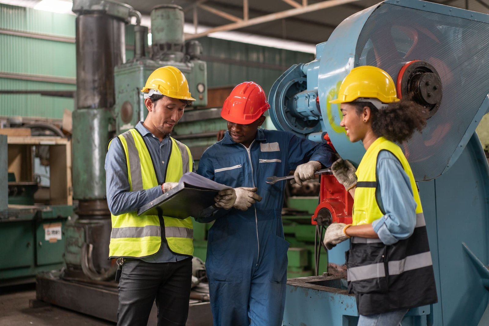 Male and female engineers look at machine specification documents for machine repair at factory
